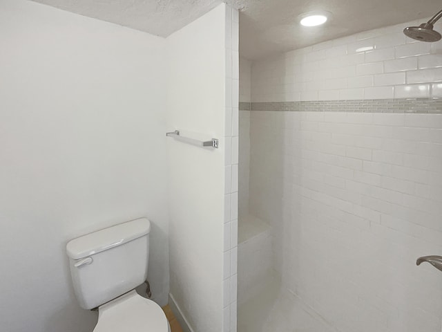 bathroom with a tile shower, a textured ceiling, and toilet