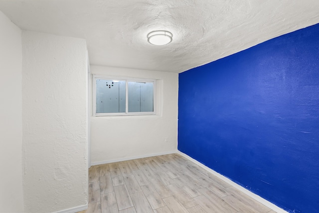 empty room with a textured ceiling and light wood-type flooring