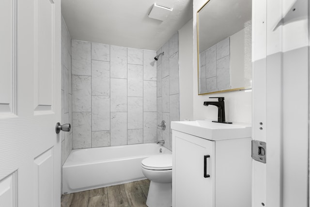 full bathroom featuring vanity, tiled shower / bath, wood-type flooring, and toilet