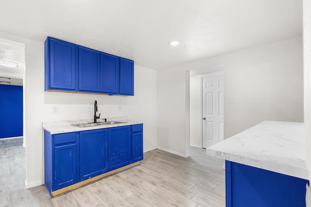 kitchen with blue cabinets, sink, and light hardwood / wood-style flooring