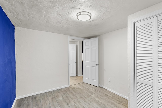 unfurnished bedroom with a closet, a textured ceiling, and light hardwood / wood-style flooring