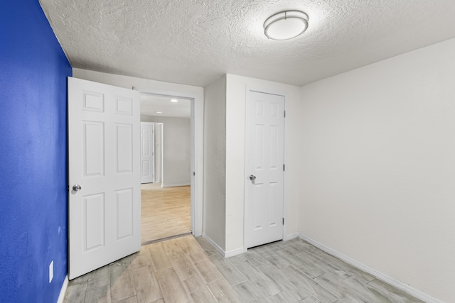 unfurnished bedroom featuring light hardwood / wood-style flooring, a closet, and a textured ceiling