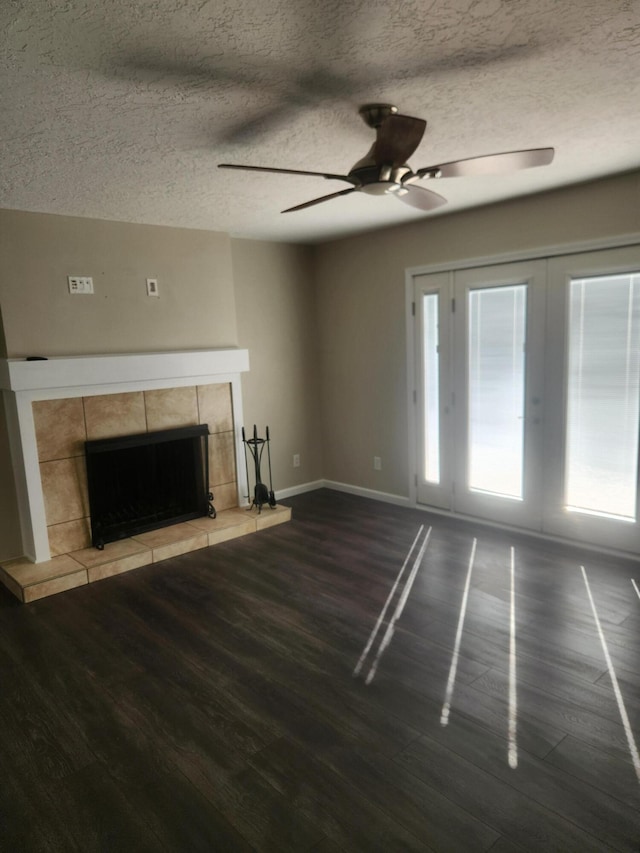 unfurnished living room with a tiled fireplace, wood-type flooring, ceiling fan, and a textured ceiling