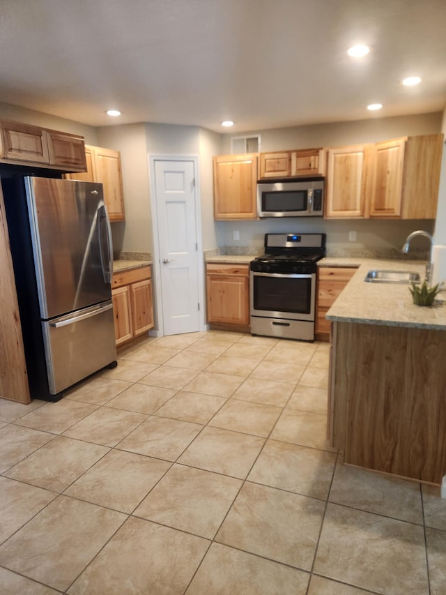 kitchen with appliances with stainless steel finishes, sink, light tile patterned floors, and light brown cabinetry