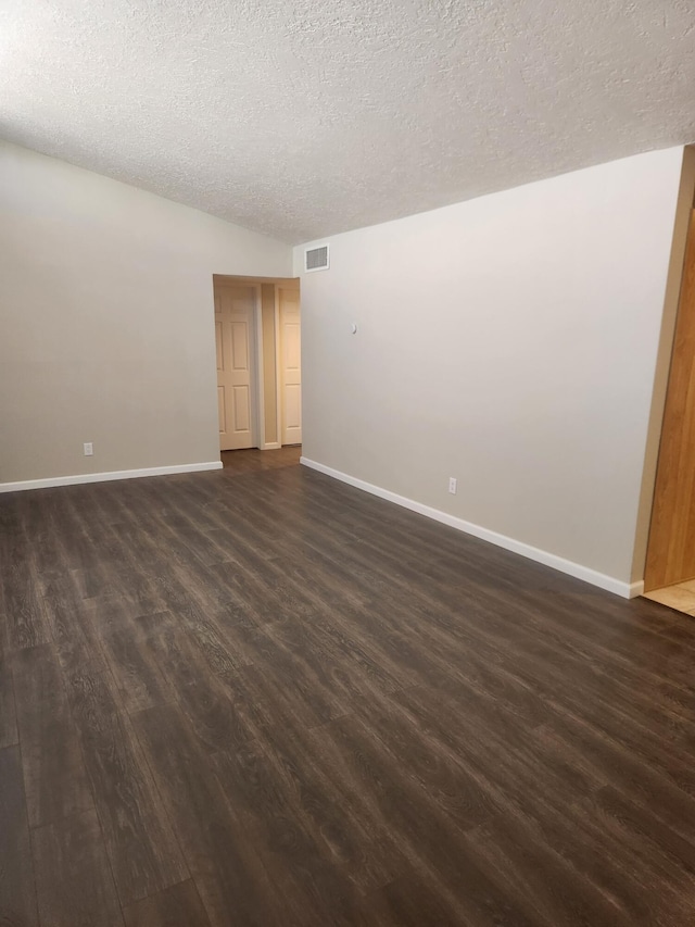 spare room featuring a textured ceiling and dark hardwood / wood-style flooring