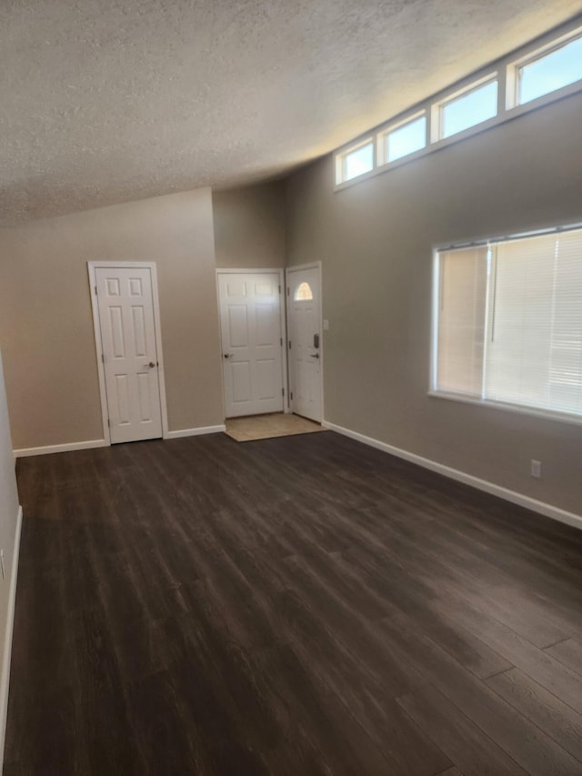 foyer with dark hardwood / wood-style flooring, lofted ceiling, and a textured ceiling