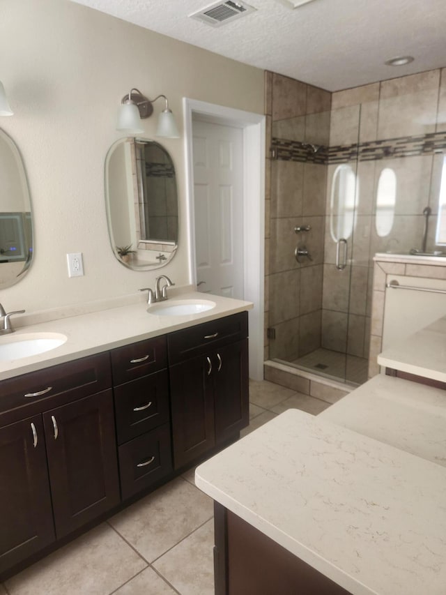 bathroom with tile patterned floors, a shower with shower door, vanity, and a textured ceiling