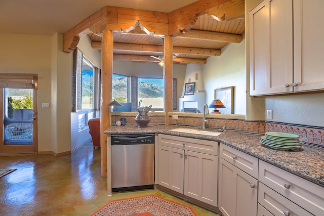 kitchen with dark stone countertops, sink, stainless steel dishwasher, and a healthy amount of sunlight