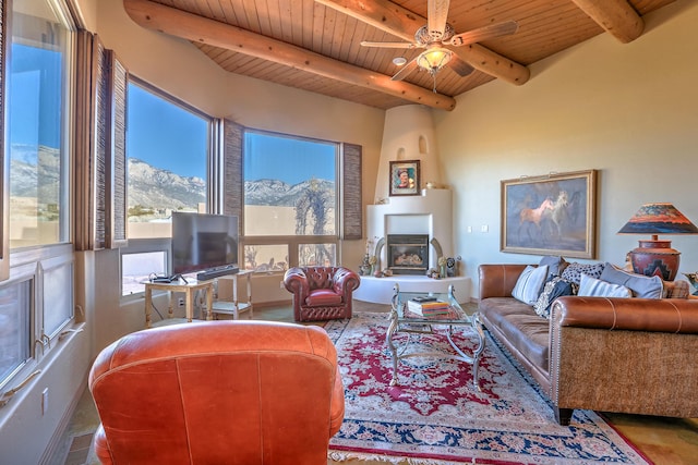 living room featuring ceiling fan, wood ceiling, a large fireplace, and beamed ceiling