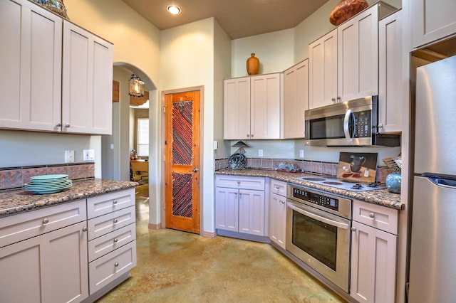 kitchen with white cabinetry, appliances with stainless steel finishes, and dark stone counters