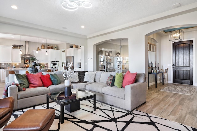 living room featuring an inviting chandelier, light hardwood / wood-style flooring, and a textured ceiling