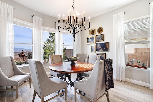 dining area with a mountain view, a chandelier, and light wood-type flooring