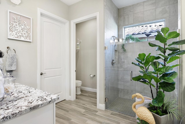 bathroom featuring vanity, hardwood / wood-style flooring, a shower with shower door, and toilet