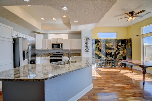 kitchen with stainless steel appliances, white cabinetry, sink, and stone countertops