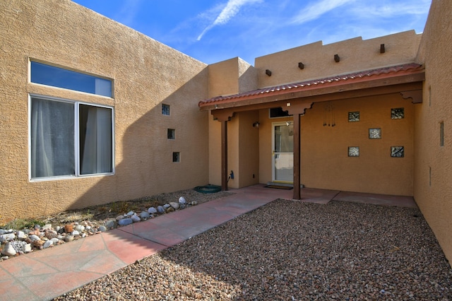 view of exterior entry with a patio area