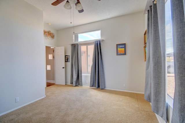 carpeted empty room with ceiling fan, a towering ceiling, and a textured ceiling