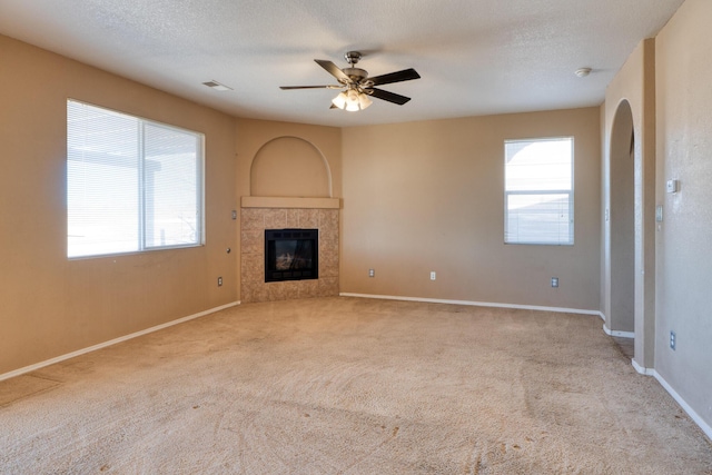 unfurnished living room featuring a healthy amount of sunlight, light carpet, and a textured ceiling