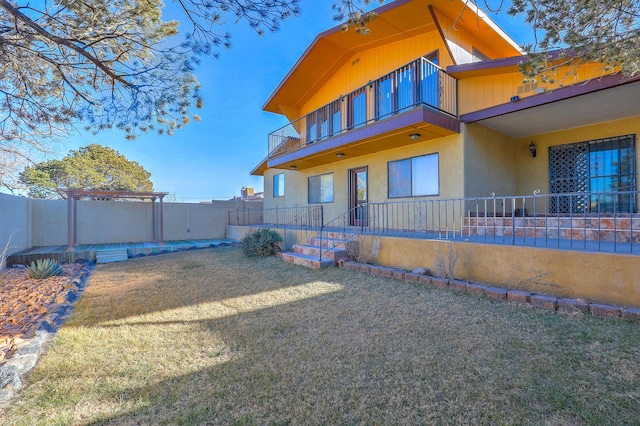 exterior space featuring a pergola, a lawn, and a balcony