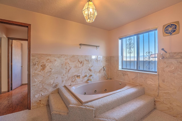 bathroom featuring a textured ceiling and tiled tub