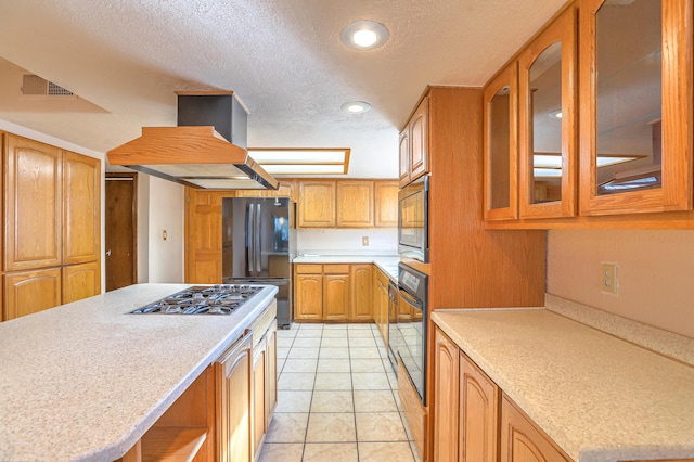 kitchen featuring island exhaust hood, light tile patterned floors, a textured ceiling, and black appliances