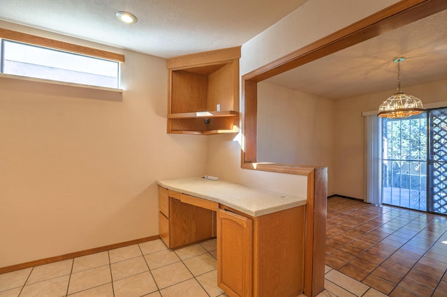 kitchen with light tile patterned flooring, a wealth of natural light, built in desk, and decorative light fixtures