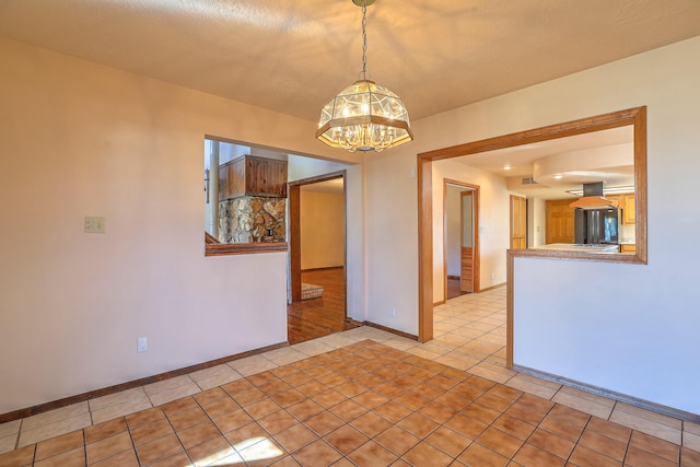 tiled empty room featuring a notable chandelier