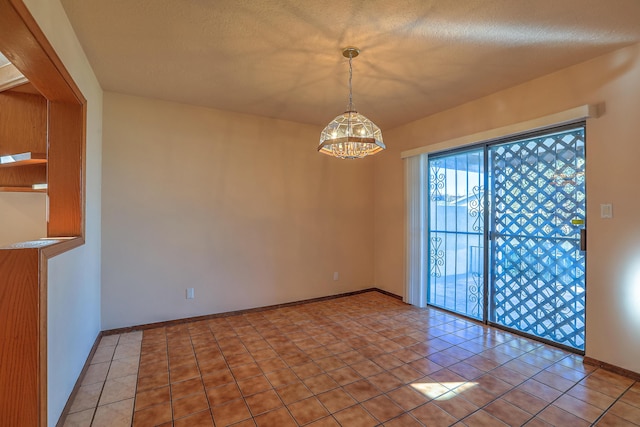 spare room with an inviting chandelier, light tile patterned floors, and a textured ceiling