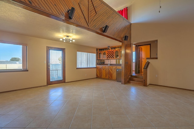 unfurnished living room with light tile patterned flooring, plenty of natural light, and a textured ceiling