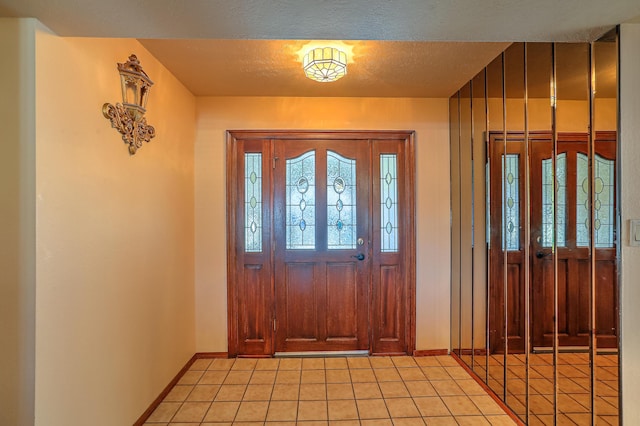 foyer with light tile patterned floors and a textured ceiling