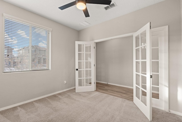 unfurnished room with light colored carpet, a textured ceiling, ceiling fan, and french doors