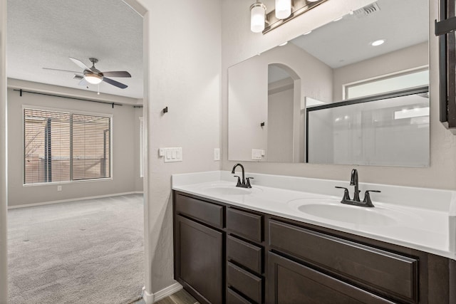 bathroom featuring vanity, ceiling fan, a shower with shower door, and a textured ceiling