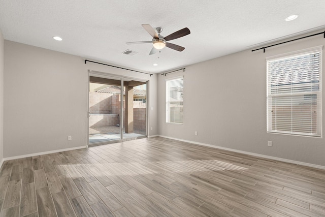 unfurnished room with ceiling fan, light hardwood / wood-style flooring, and a textured ceiling