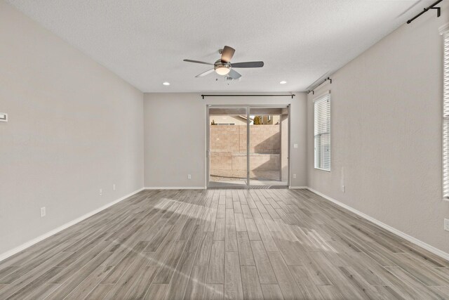 unfurnished room featuring ceiling fan, light hardwood / wood-style floors, and a textured ceiling