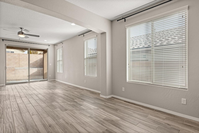 spare room with ceiling fan, light hardwood / wood-style flooring, and a textured ceiling