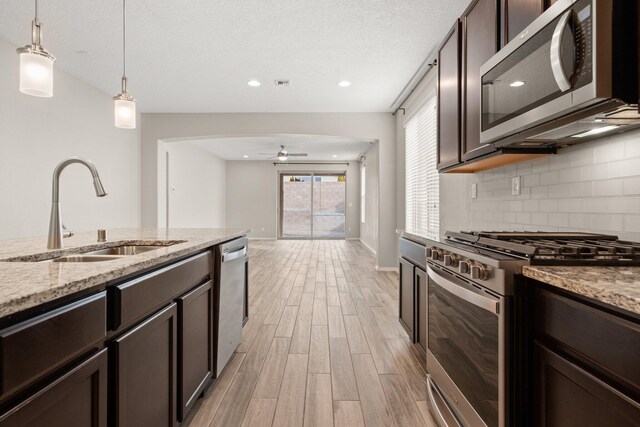 kitchen with sink, light stone counters, tasteful backsplash, pendant lighting, and stainless steel appliances