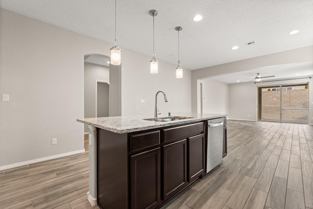 kitchen with pendant lighting, sink, a kitchen island with sink, dark brown cabinets, and stainless steel dishwasher