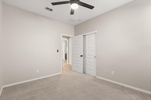 unfurnished bedroom with light carpet, a closet, and ceiling fan