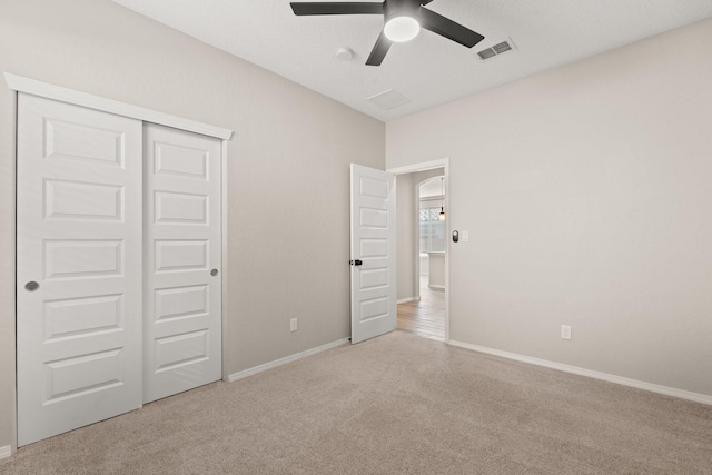 unfurnished bedroom with light colored carpet, ceiling fan, and a closet