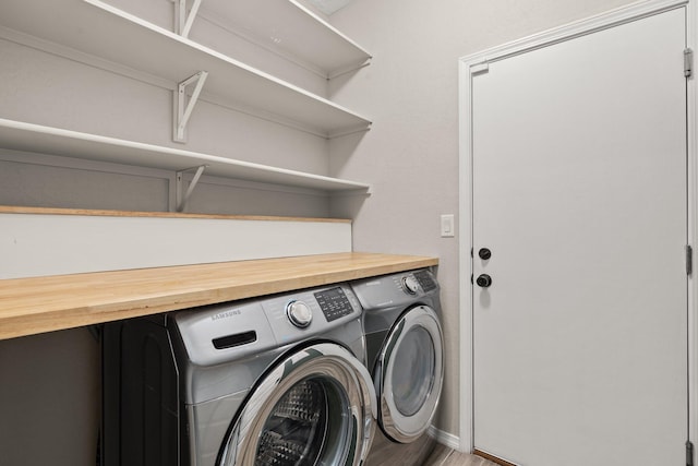 clothes washing area with separate washer and dryer and hardwood / wood-style floors