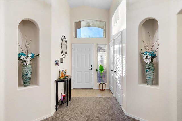 entryway featuring a high ceiling and light colored carpet