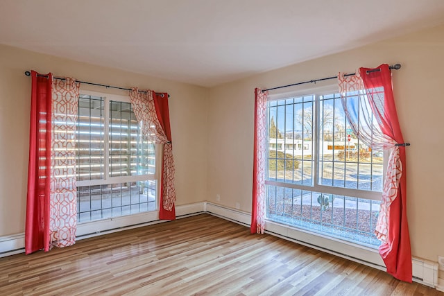 unfurnished room featuring a baseboard heating unit, a baseboard radiator, and wood finished floors