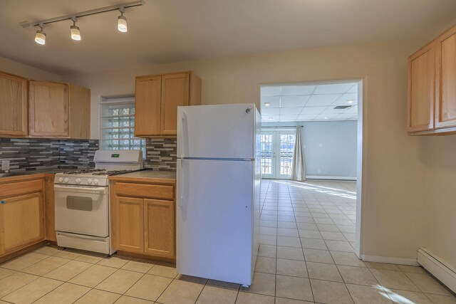 kitchen with light tile patterned floors, decorative backsplash, a baseboard heating unit, white appliances, and baseboards