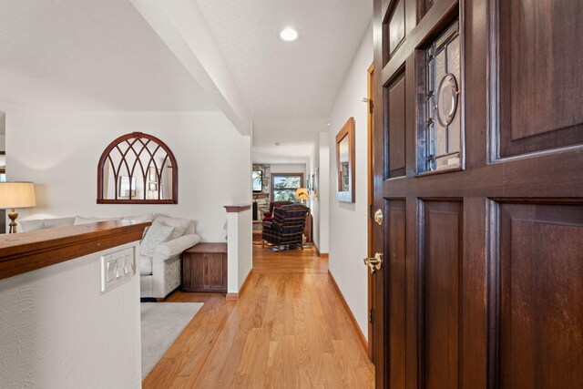 entryway featuring light wood-style flooring, a textured ceiling, and baseboards