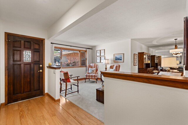 foyer featuring light wood-type flooring, baseboards, and a notable chandelier