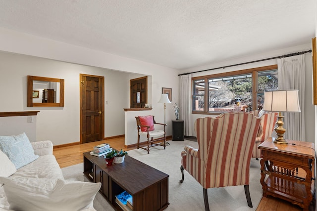 living area with baseboards, light wood finished floors, and a textured ceiling