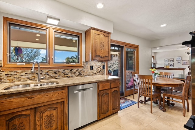 kitchen featuring a sink, tasteful backsplash, brown cabinetry, light tile patterned floors, and dishwasher