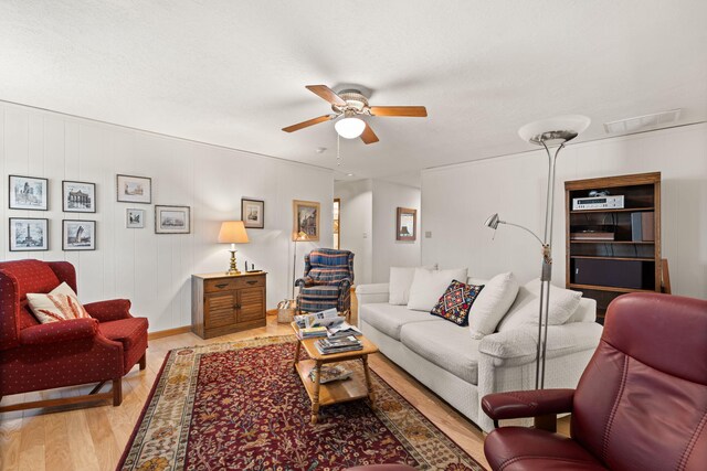 living area with visible vents, a ceiling fan, and light wood finished floors