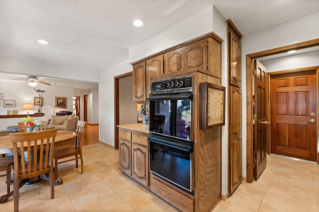 kitchen featuring light tile patterned flooring, a textured ceiling, and dobule oven black