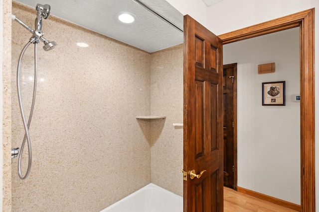 full bathroom featuring wood finished floors, baseboards, and a textured ceiling