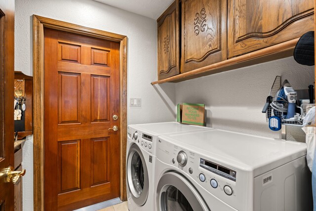 laundry area featuring a textured wall, cabinet space, and washer and clothes dryer